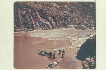 The Hatch party looking over Bedrock Rapid. The 10-man inflated craft with motor and the Jones' aluminum canoe-type boat are shown on the beach. The boloney fouled the rock in the attempt to run